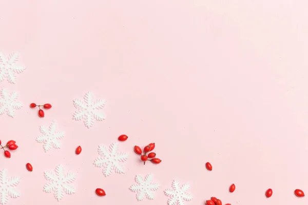 コピースペース付きのエレガントな冬の背景 淡いピンクの背景に赤い果実と雪のフレーク クリスマス 冬の休日 新年のコンセプト — ストック写真
