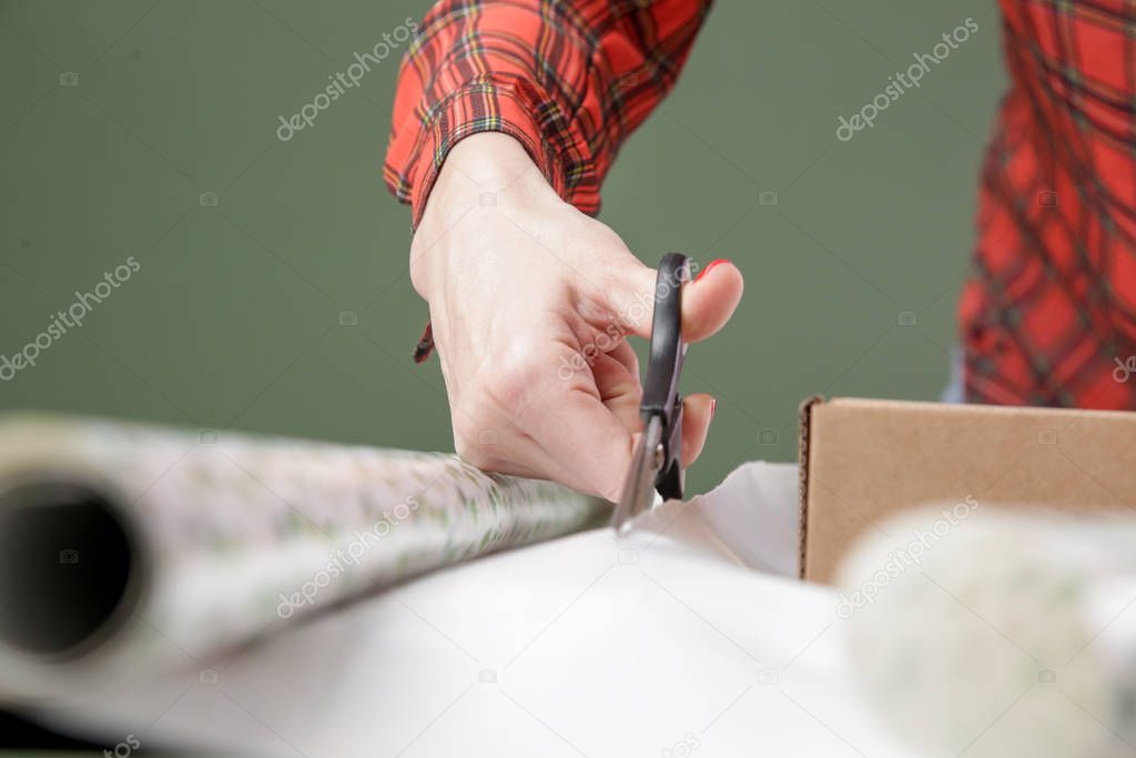 Woman cutting wrapping paper on the desk, holiday season gifting concept