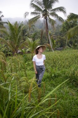 Geleneksel bir kadın. Terasta bambu şapka takıyor.