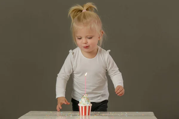 カップケーキから誕生日のろうそくを吹いている幼児の女の子のスタジオショット — ストック写真