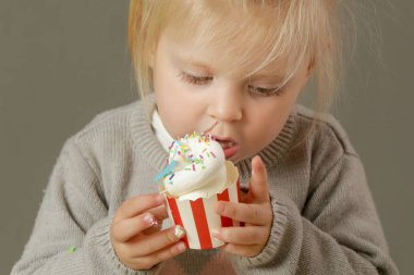 Krem şantili kek yiyen bir çocuğun stüdyo fotoğrafı.