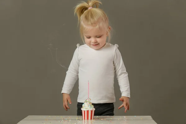 カップケーキから誕生日のろうそくを吹いている幼児の女の子のスタジオショット — ストック写真