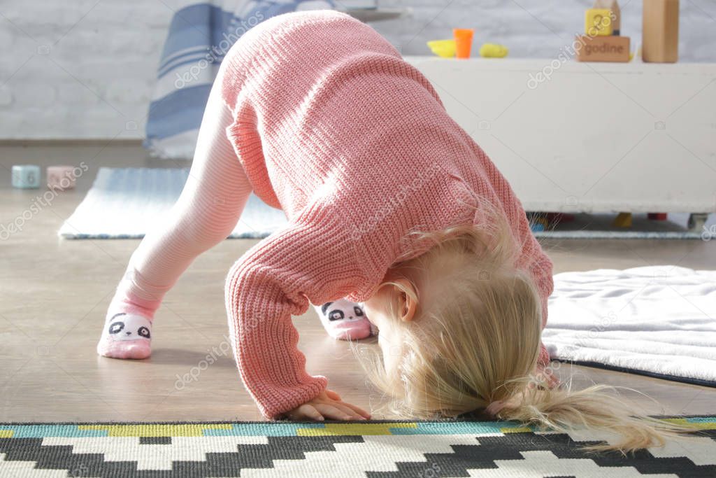 Two years old toddler girl learning to roll forward