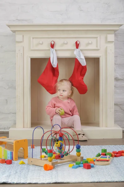 可爱的蹒跚学步的小女孩在装饰着红色圣诞袜的木制壁炉前室内玩耍 在家里过冬 — 图库照片