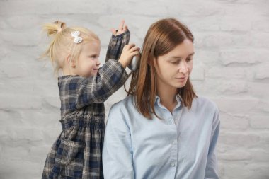 Küçük kız annesinin saçını tarıyor.