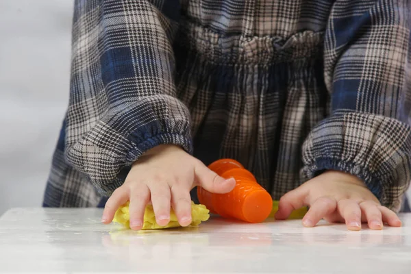 Toddler girl playing with modelling clay. Play dough allows kids to develop fine motor skills, strengthen fingers, hands and wrists and to be naturally curious and explore the world using their senses