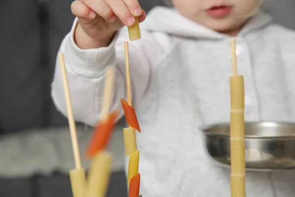 : Fine motor pasta threading activity for kids. An easy and fun tower building challenge that works on fine motor skills as well as hand eye coordination.