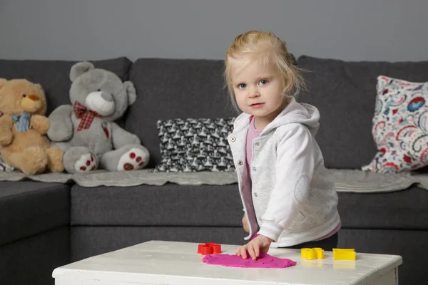 Toddler girl playing with modelling clay. Play dough allows kids to develop fine motor skills, strengthen fingers, hands and wrists and to be naturally curious and explore the world using their senses