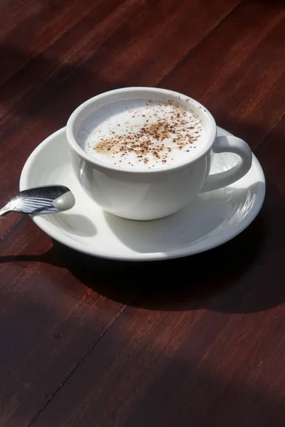 A cup of hot fresh coffee with rich foam on the wooden table
