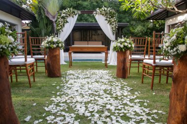 Tropik bahçede güzel romantik bir düğün, ahşap sandalyeler ve beyaz çiçeklerle süslenmiş basit bir çardak.
