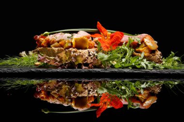 Açık yüzlü sandviç, jambonlu kızarmış tahıl ekmeği, peynir, otlar ve siyah üzerine yeşil yaprak salatası.