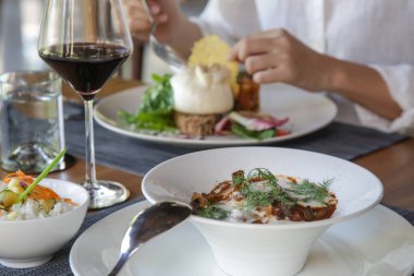 Güzel dekore edilmiş yemekler ve ahşap masada bir bardak kırmızı şarap.