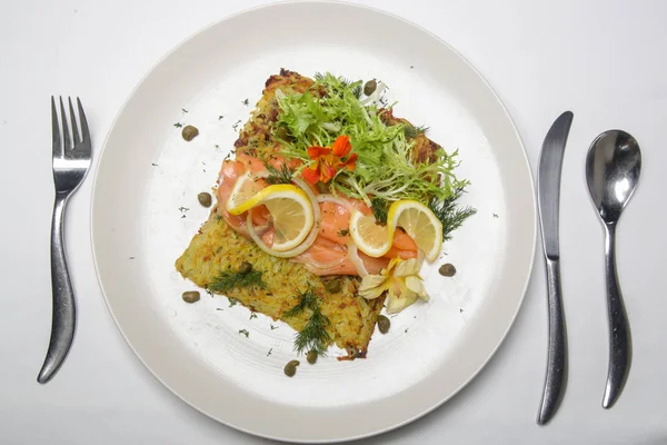 緑のサラダとレモンのスライスで飾られたジャガイモのフリッターでスモークサーモン 絶妙な料理 創作料理のコンセプト — ストック写真