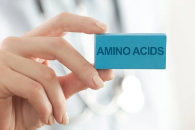 Doktor tavsiye ediyor. Tıp işçisi Amino Acids tabelalarını tutuyor..