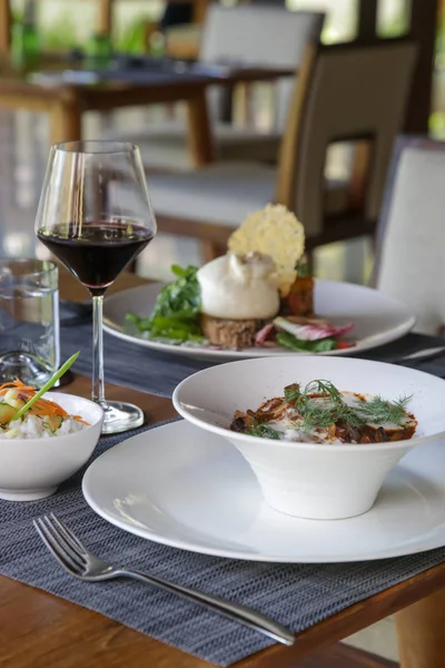 Güzel dekore edilmiş yemekler ve ahşap masada bir bardak şarap.
