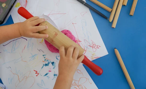 Toddler girl playing with modelling clay. Play dough allows kids to develop fine motor skills, strengthen fingers, hands and wrists and to be naturally curious and explore the world using their senses