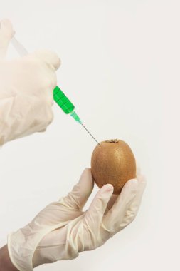 Genetik olarak tasarlanmış gıda konsepti olan kivi meyvesine enjekte edilen iğnenin yakın çekimi.