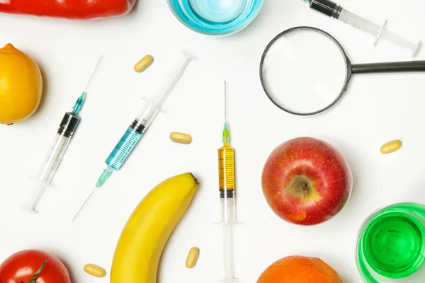 Genetically engineered food concept, fruits and vegetables flat lay with syringes and needles,problem of toxins in food
