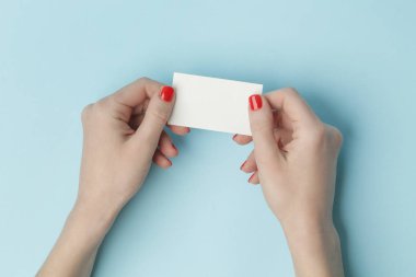 Woman hands holding blank card on blue table