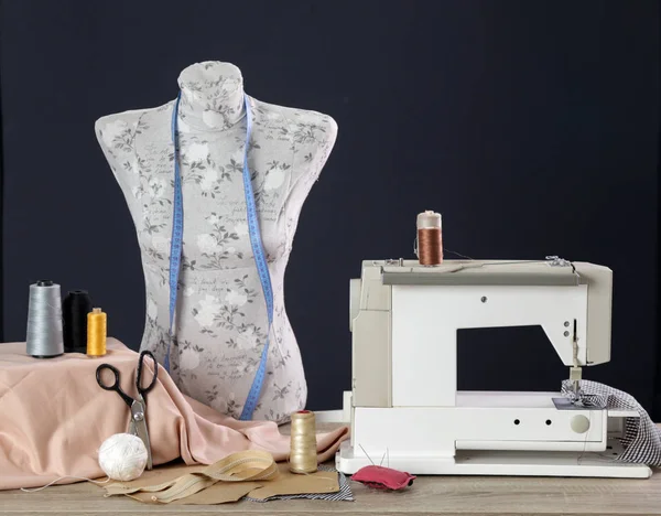 Sewing equipment and mannequin doll against black background
