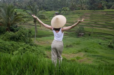 Geleneksel bir kadın. Terasta bambu şapka takıyor.