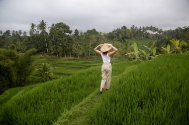 Geleneksel bir kadın. Terasta bambu şapka takıyor.