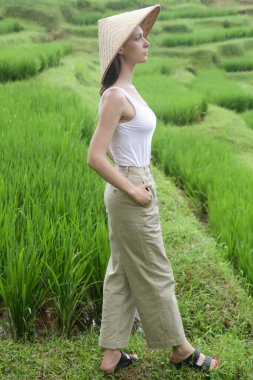 Geleneksel bir kadın. Terasta bambu şapka takıyor.