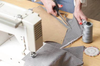 Terzi kadın makasla kumaş kesiyor. Moda tasarımcısı moda stüdyosunda kumaşla çalışıyor..