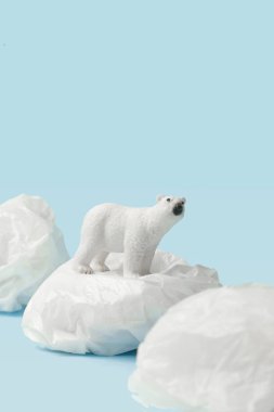 Beyaz kutup ayısı mavi zemin üzerinde plastik torba, plastik kirlilik ve iklim değişikliği kavramı