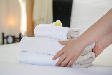 Oda servisi. Otel odasında havlu değiştiren kadın. Housecleaner yatağa havlu koyarak, müşterilerin taşınması için her şeyi hazırlanıyor