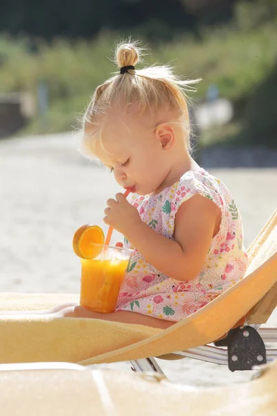 Roztomilé Blondýny Batole Dívka Sedí Lehátku Popíjí Čerstvé Squizeed Pomerančový — Stock fotografie