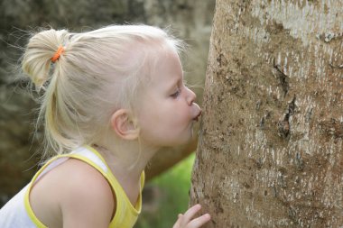 Küçük çocuk ağaca sarılıyor. Ağaca sarılmak sağlığın için iyi olabilir. Hormon oksitosin, serotonin ve dopamin seviyelerini arttırır. Bu da sakin hissetmenizi sağlar ve sizi daha mutlu eder.