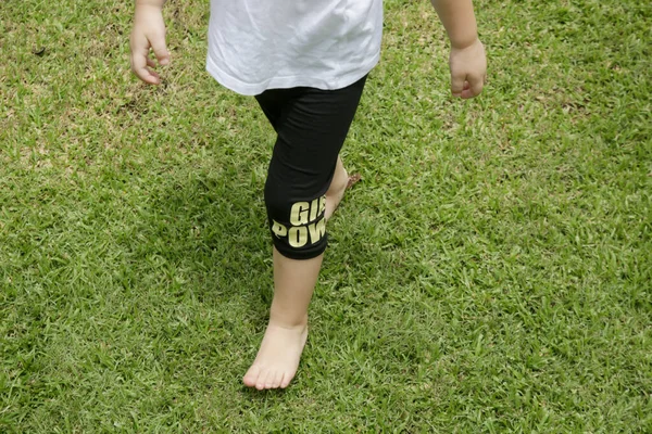 緑の芝生の上で裸足で走る子供 裸足で歩くことは 足の筋肉や靭帯を開発するのに役立ちます そして足のアーチを強化し それは彼らのモーター開発のために非常に有益である — ストック写真