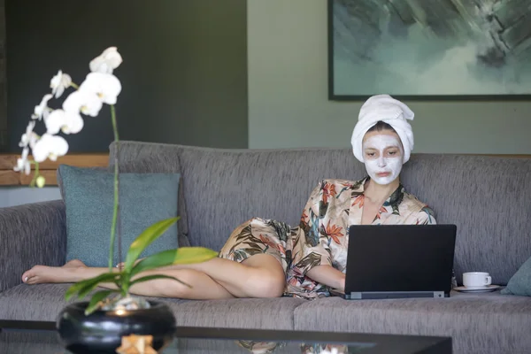 ラップトップの前に顔の美しさのマスクをして家に座っている若い女性 家での居心地の良い時間 セルフタイムとホームスパのコンセプト コロナウイルスの発生と自己隔離の概念 — ストック写真