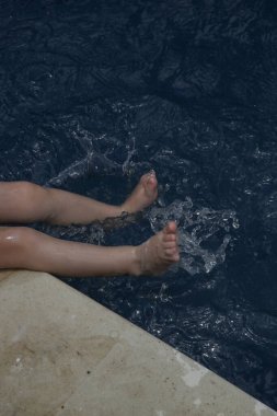 Bacaklarına güneş kremi süren tatlı küçük bir kız çocuğu. Yaz tatilinde bebeği güneşten korumak için güneş kremi. Yolculuk sırasında çocuk sağlığı ve cilt bakımı.