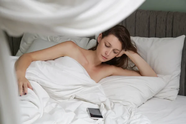 Droevige Depressieve Jonge Vrouw Ligt Bed Kijkt Naar Haar Mobiele — Stockfoto