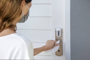 Coronavirus COVID-19 önleme. Kadın, virüsü öldürmek için antibakteriyel dezenfektanla kapı kolunu siliyor. Ev hijyeni..