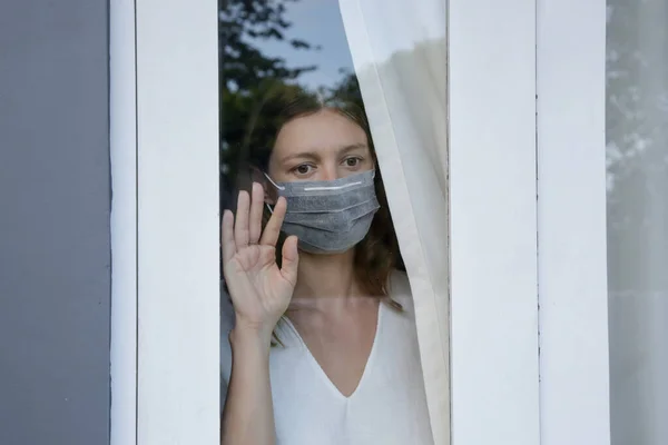 Jovem Com Máscara Cirúrgica Descartável Olhando Para Fora Através Janela — Fotografia de Stock