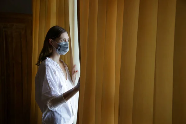 Jeune Femme Avec Masque Chirurgical Jetable Regardant Par Fenêtre Ennuyé — Photo