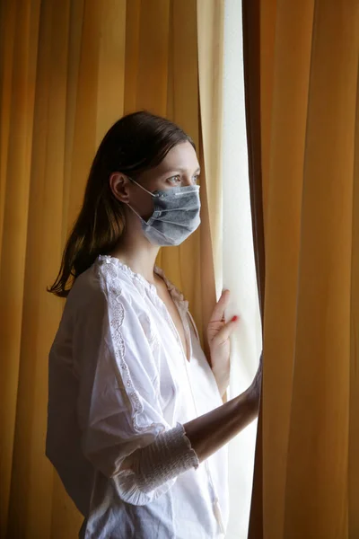 Giovane Donna Con Maschera Chirurgica Monouso Guardando Fuori Attraverso Finestra — Foto Stock