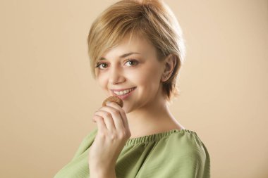 Çikolata parçacıklı kurabiye yiyen mutlu genç bir kadının stüdyo fotoğrafı.