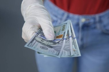Ellerinde kağıt banknotlar tutan lastik eldivenlerle korunan eller