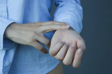 Kadın bileğinin içine iki parmağını koyarak nabzını kontrol ediyor..