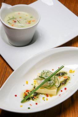 Lokanta masasında salsa verde soslu soya bifteği ve kremalı sebze çorbası servis ediliyor.