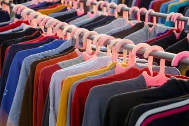 İkinci el dükkanında ya da ikinci el mağazasında çalışan erkekler, kadınlar ve çocuklar için çok sayıda kullanılmış kıyafet var. Moda endüstrisinde atık sorunu kavramı.