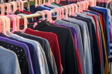 İkinci el dükkanında ya da ikinci el mağazasında çalışan erkekler, kadınlar ve çocuklar için çok sayıda kullanılmış kıyafet var. Moda endüstrisinde atık sorunu kavramı.