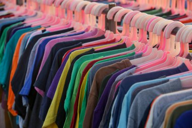 İkinci el dükkanında ya da ikinci el mağazasında çalışan erkekler, kadınlar ve çocuklar için çok sayıda kullanılmış kıyafet var. Moda endüstrisinde atık sorunu kavramı.