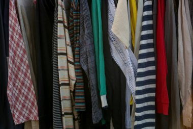 İkinci el dükkanında ya da ikinci el mağazasında çalışan erkekler, kadınlar ve çocuklar için çok sayıda kullanılmış kıyafet var. Moda endüstrisinde atık sorunu kavramı.