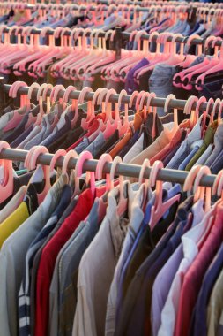 İkinci el dükkanında ya da ikinci el mağazasında çalışan erkekler, kadınlar ve çocuklar için çok sayıda kullanılmış kıyafet var. Moda endüstrisinde atık sorunu kavramı.