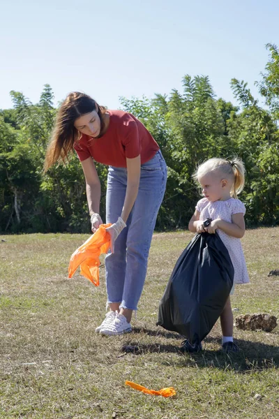 Giovane Donna Raccogliendo Rifiuti Plastica Dal Prato Con Sua Bambina — Foto Stock